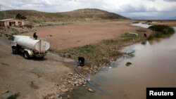 FILE - A water truck pomps water from Desaguadero river during the worst drought in 25 years near Oruro, Bolivia, Dec. 1, 2016. 