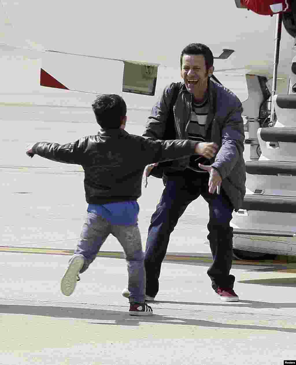 Freed El Mundo Middle East correspondent Javier Espinosa laughs as his son runs towards him after his arrival at Torrejon de Ardoz airbase near Madrid, Spain, March 30, 2014.