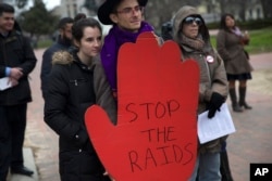 Diego Arene and Adele Anderson of Washington listen to demonstrators outside the White House in Washington, Jan. 15, 2016, calling for an end to immigration raids.