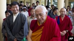 Newly elected PM Lobsang Sangay, left, and outgoing PM Samdhong Rinpoche, center, walk out of the prayer hall at the Tsuglakhang temple in Dharmsala, India, August 3, 2011