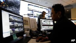 In this July 30, 2019, photo, Sandra Swint, right, campus security associate for Fulton County School District and Paul Hildreth, background, the district’s emergency operations coordinator, work in the emergency operations center at the Fulton County School District.