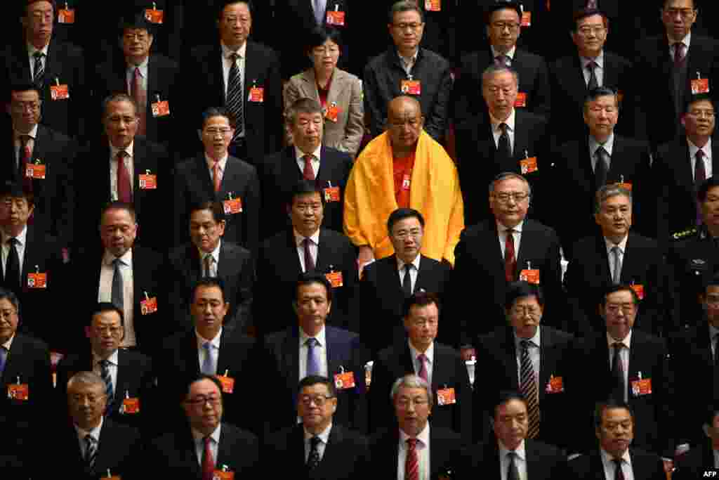 A Buddhist delegate appears amongst other delegates as they stand during the national anthem at the closing session of the Chinese People&#39;s Political Consultative Conference at the Great Hall of the People in Beijing.