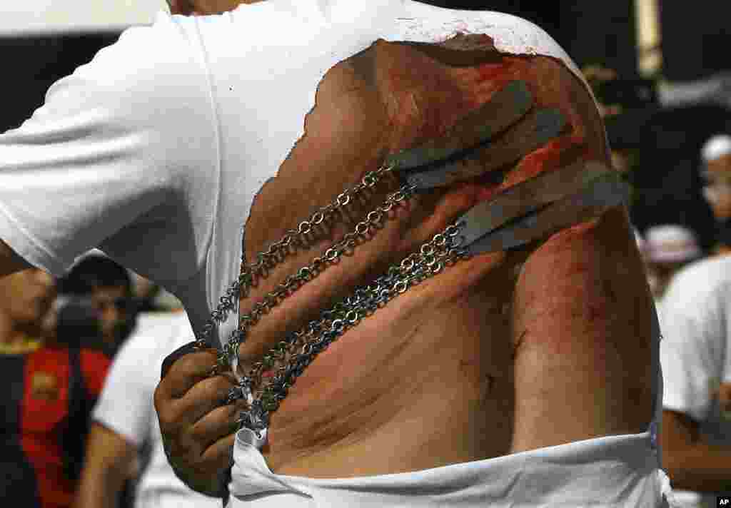 A Lebanese Shi'ite man strikes his back with knifes to show his grief during Ashura rituals in the southern market town of Nabatieh, Oct. 12, 2016. 