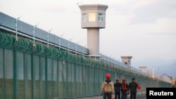 FILE PHOTO: Workers walk by the perimeter fence of what is officially known as a vocational skills education center in Dabancheng in Xinjiang Uighur Autonomous Region, China,Sept. 4, 2018. 