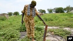 Un soldat du gouvernement inspecte une roquette découverte après des affrontements récents avec des rebelles à Kuek, dans le nord du Haut-Nil, Soudan du Sud, 19 août 2017.