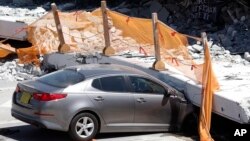 A crushed car is shown under a section of a collapsed pedestrian bridge, Friday, March 16, 2018 near Florida International University in the Miami area.