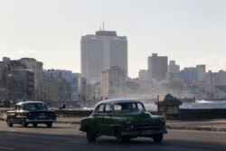 FILE - Vintage cars drive on the seafront boulevard El Malecon in Havana, Cuba, December 29, 2020.