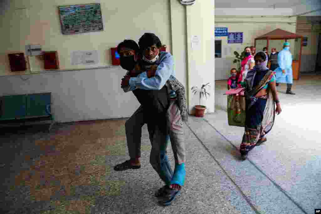 A man carries another on his back as he brings him for medical check up at a government hospital in Jammu, India.