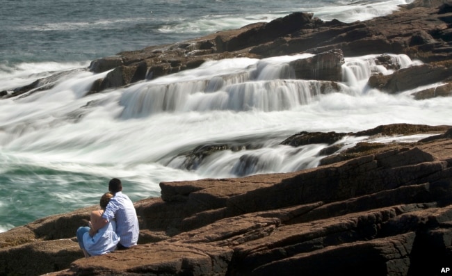 People watch the surf recede over the rocky coast off Acadia's Mount Desert Island (AP)