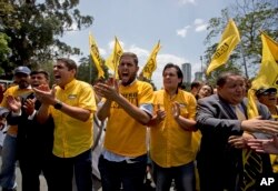 Opposition lawmakers, Jose maul Olivares, left, Juan Requesens, second left, Carlos Paparoni, second right, and Jose Brito, shout "Elections now" during a protest at the Ombudsman's office in Caracas, Venezuela, April 3, 2017.