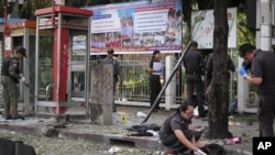 Police and forensic experts investigate the site where a man was injured when a bomb he was carrying exploded, in central Bangkok February 14, 2012.