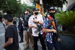 FILE - A Texas Guerrillas member who calls himself "Apex," third from right, and others carry weapons at a Black Lives Matter rally in Austin, Texas, Aug. 1, 2020.