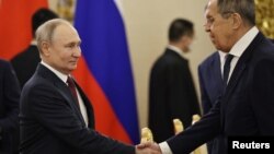Le président russe Vladimir Poutine (à g.) serre la main du ministre des Affaires étrangères Sergueï Lavrov au Kremlin à Moscou, le 21 mars 2023.
