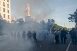 FILE - Tear gas floats in the air as a line of police move demonstrators away from St. John's Church across Lafayette Park from the White House, as they gather to protest the death of George Floyd, in Washington, June 1, 2020.