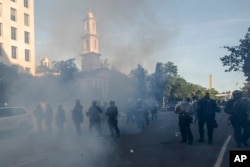 Tear gas floats in the air as a line of police move demonstrators away from St. John's Church across Lafayette Park from the White House, as they gather to protest the death of George Floyd, Monday, June 1, 2020, in Washington.
