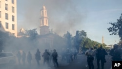 FILE - Tear gas floats in the air as a line of police move demonstrators away from St. John's Church at Lafayette Park near the White House, as they gather to protest the death of George Floyd, June 1, 2020, in Washington. 