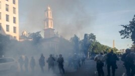 Tear gas floats in the air as a line of police move demonstrators away from St. John's Church across Lafayette Park from the White House, as they gather to protest the death of George Floyd, Monday, June 1, 2020, in Washington.