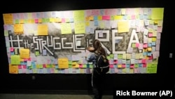 In this November 14, 2019, photo, a student attaches a note to the Resilience Project board on the campus of Utah Valley University, in Orem, Utah. The purpose of the project is to let students know that it is OK to struggle. (AP Photo/Rick Bowmer)