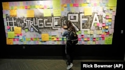 In this November 14, 2019, photo, a student attaches a note to the Resilience Project board on the campus of Utah Valley University, in Orem, Utah. The purpose of the project is to let students know that it is OK to struggle. (AP Photo/Rick Bowmer)