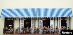 FILE - Tourists sit on a balcony at a restaurant in Old Havana, Cuba, April 28, 2017.