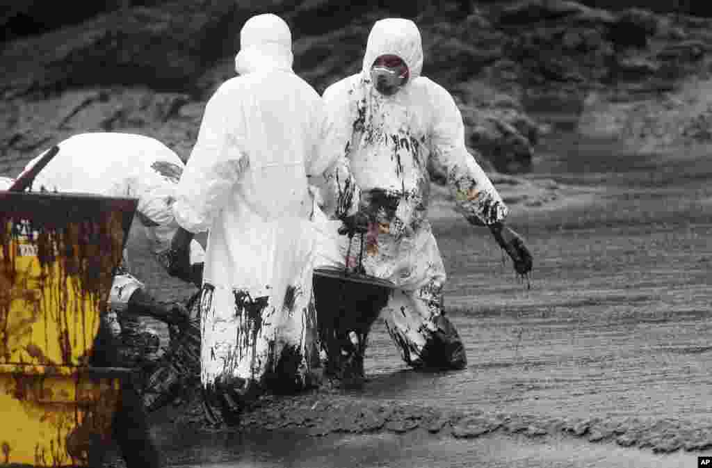 Workers remove crude oil during a clean up operation on the beach of Prao Bay on Samet Island in Rayong province eastern Thailand. About 50,000 liters (13,200 gallons) of crude oil that leaked from a pipeline operated by PTT Global Chemical Plc, has reached the popular tourist island in the country&#39;s eastern sea despite continuous attempts to clean it up.