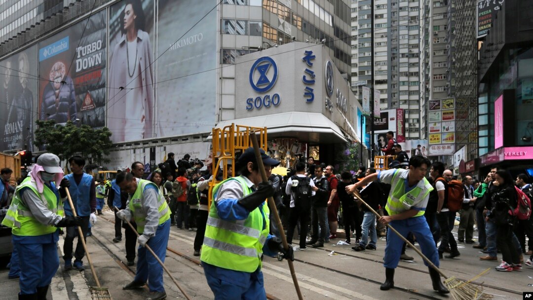 Para pekerja menyapu jalanan setelah pihak berwenang membongkar barikade dan tenda di jalanan utama district Causeway Bay, Hong Kong yang dikuasai para pengunjuk rasa (15/12).