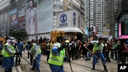 Para pekerja menyapu jalanan setelah pihak berwenang membongkar barikade dan tenda di jalanan utama district Causeway Bay, Hong Kong yang dikuasai para pengunjuk rasa (15/12).