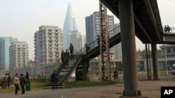FILE - North Koreans walk on a pedestrian bridge in Pyongyang.