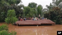 FILE - Villagers take refuge on a rooftop above flood waters from a collapsed dam in the Attapeu district of southeastern Laos, July 24, 2018.