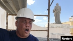 Jesus Santos sings operatic love songs while repairing plaster to a Hurricane Maria damaged facade at Cathedral of San Juan Bautista in San Juan, Puerto Rico on Oct. 4, 2017.