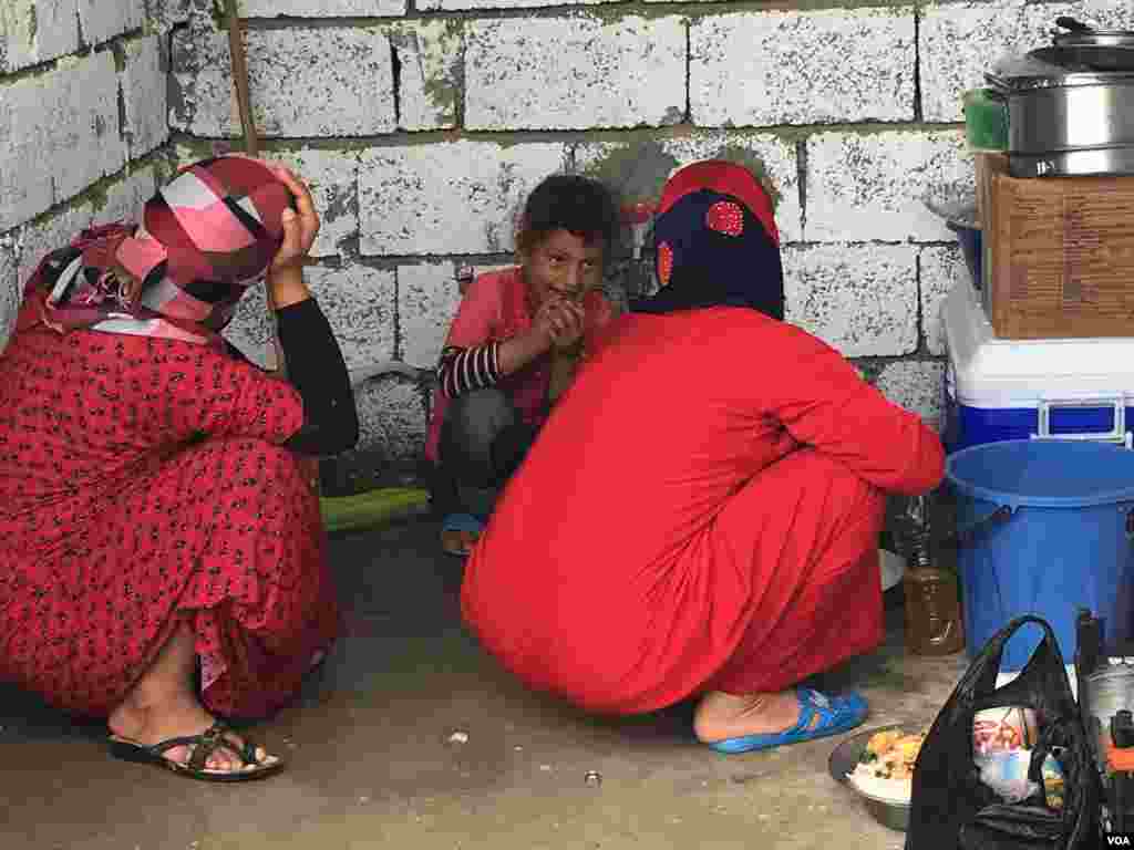 Women who fled IS hide their faces as they work in a makeshift kitchen in a refugee camp outside Makhmour, Iraq, April 11, 2016. (S. Behn/VOA)