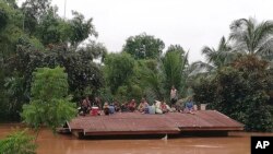 Penduduk desa naik ke atap untuk menyelamatkan diri dari banjir akibat bendungan yang runtuh di distrik Attapeu, Laos tenggara, Selasa, 24 Juli 2018.