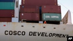 In this photo provided by the Georgia Port Authority, a crewman on board the container ship Cosco Development looks over the side as the vessel docks at the Port of Savannah, May 11, 2017, in Garden City, Georgia.