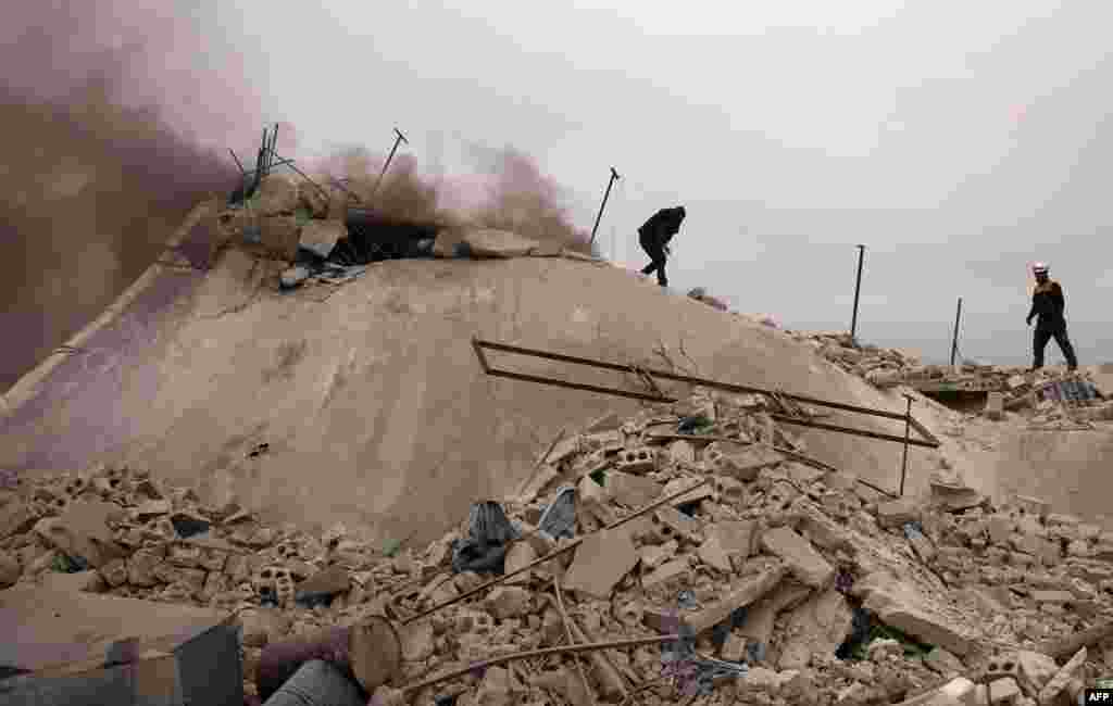 Rescue workers known as the White Helmet search for victims in a house that was destroyed during a pro-regime forces airstrike outside Aleppo, Syria.