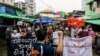 FILE - A man records protesters on his mobile phone as they take part in a demonstration against the military coup, in Yangon, Myanmar, May 21, 2021. 