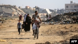 Gazzeliler, El Burayj kampında yıkılan binaların arasından geçerken- 2 Haziran 2024.
