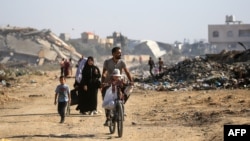 Palestinos recorren un camino bordeado de edificios destruidos en el campamento de Al Bureij, en el centro de la Franja de Gaza, el 2 de junio de 2024, en medio del conflicto en curso entre Israel y el grupo militante palestino Hamás.