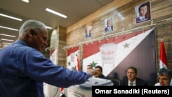 Seorang pria memasukkan surat suara untuk pemilihan presiden di Kementerian Informasi di Damaskus, Suriah, 26 Mei 2021. (Foto: Omar Sanadiki/Reuters)