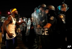 A man yells at police in riot gear just before a crowd turned violent, Sept. 16, 2017, in University City, Mo.