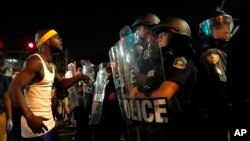 A man yells at police in riot gear just before a crowd turned violent, Sept. 16, 2017, in University City, Mo.