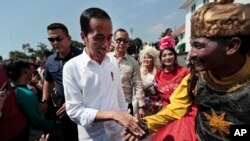  Indonesian President Joko Widodo, center, is greeted by a street busker during his visit at the Old Town in Jakarta, Indonesia, Friday, 26, 2019. Widodo said he will push ahead with sweeping and potentially unpopular economic reforms.