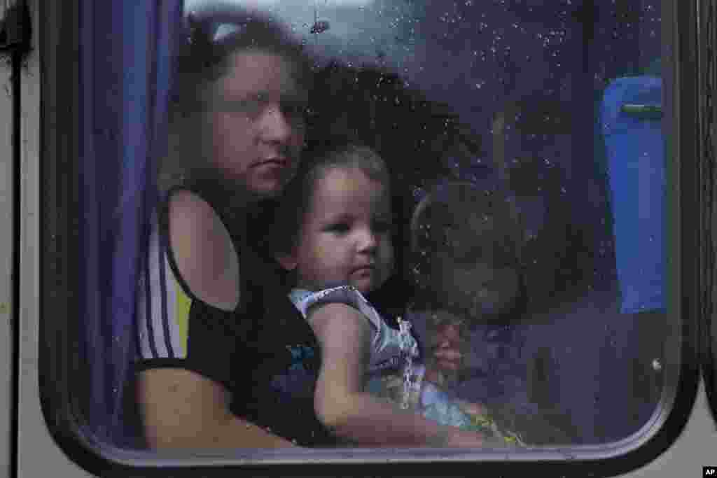 Children and their mother look through a bus window while leaving the city fearing shelling attacks during a fighting between Ukrainian government forces and pro-Russian militants in Slovyansk, May 29, 2014. 