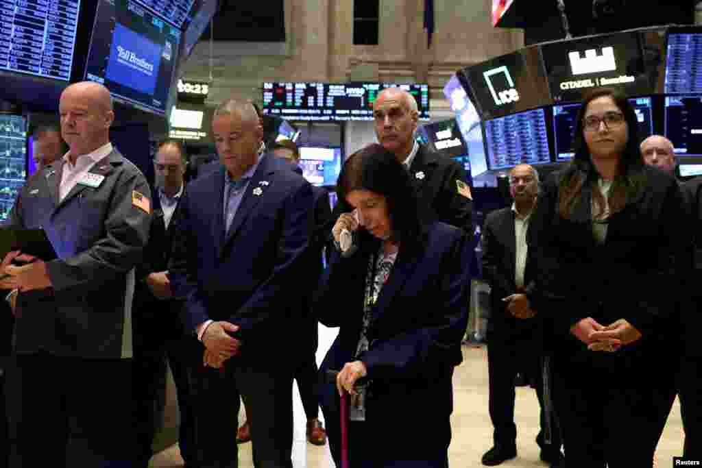 Traders and employees pause during a moment of silence, on the 23rd anniversary of the September 11, 2001 attacks, on the floor at the New York Stock Exchange.