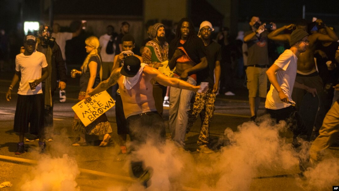 Seorang demonstran menendang kaleng gas air mata ke arah polisi dalam protes atas penembakan Michael Brown dekat Ferguson, Missouri (17/8).