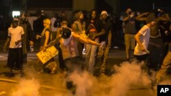 Um manifestante pontapeia uma lata de gás lacrimogéneo lançada durante o protesto em Ferguson, Missouri. Agosto 17, 2014