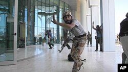 Rebel fighters and a television cameraman take shelter as an intense gun battle erupted outside the Corinthia hotel, where many foreign journalists are staying, in Tripoli, Libya, August 25, 2011