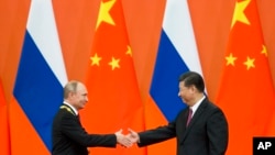 블라디미르 푸틴 러시아 대통령과 시진핑 중국 국가주석이 8일 베이징 인민대회당에서 만나 악수하고 있다. 