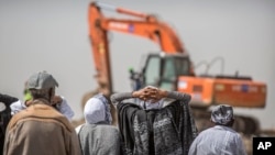 FILE - Ethiopian relatives of crash victims mourn as a mechanical digger operates at the scene where the Ethiopian Airlines Boeing 737 Max 8 crashed shortly after takeoff killing all 157 on board, near Bishoftu, southeast of Addis Ababa, in Ethiopia, March 10, 2019. 