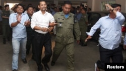 Meach Sovannara (center L), a member of the Cambodia National Rescue Party (CNRP), and a supporter of CNRP (L), are escorted by Cambodian police officers at the Phnom Penh Municipal Court, July 21, 2015. 