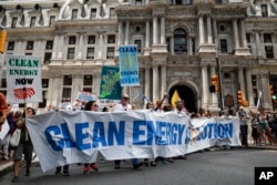 Climate change activists carry signs as they march during a protest in downtown Philadelphia ahead of the Democratic National Convention, July 24, 2016.
